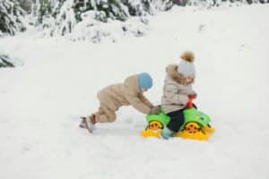Child Pushing a Friend on a small Snow Runner